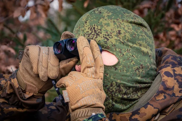 Spähender Soldat mit Zenit-BelOMO Militär-Fernglas / Binocular VKB7 im Wald